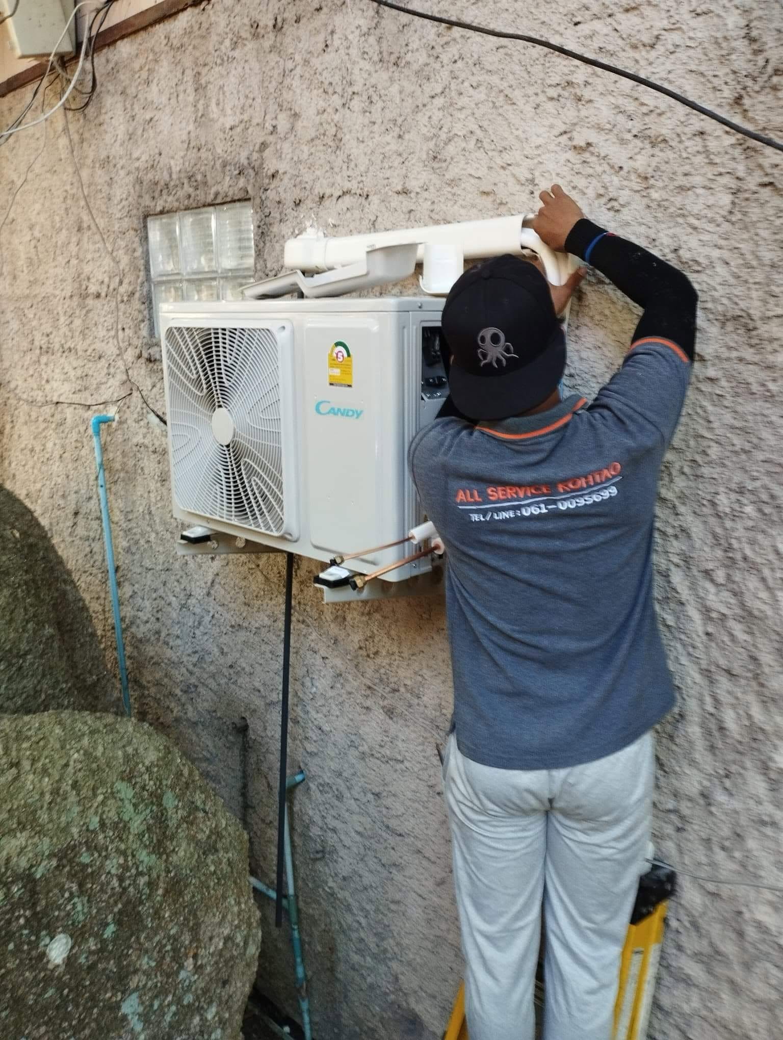 All Service Koh Tao technician installing and servicing an outdoor air conditioning unit in Koh Tao, Thailand