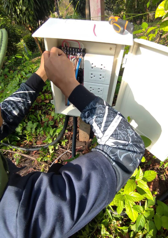 Koh Tao Engineering Group technician installing and wiring an outdoor electrical distribution box in Koh Tao, Thailand